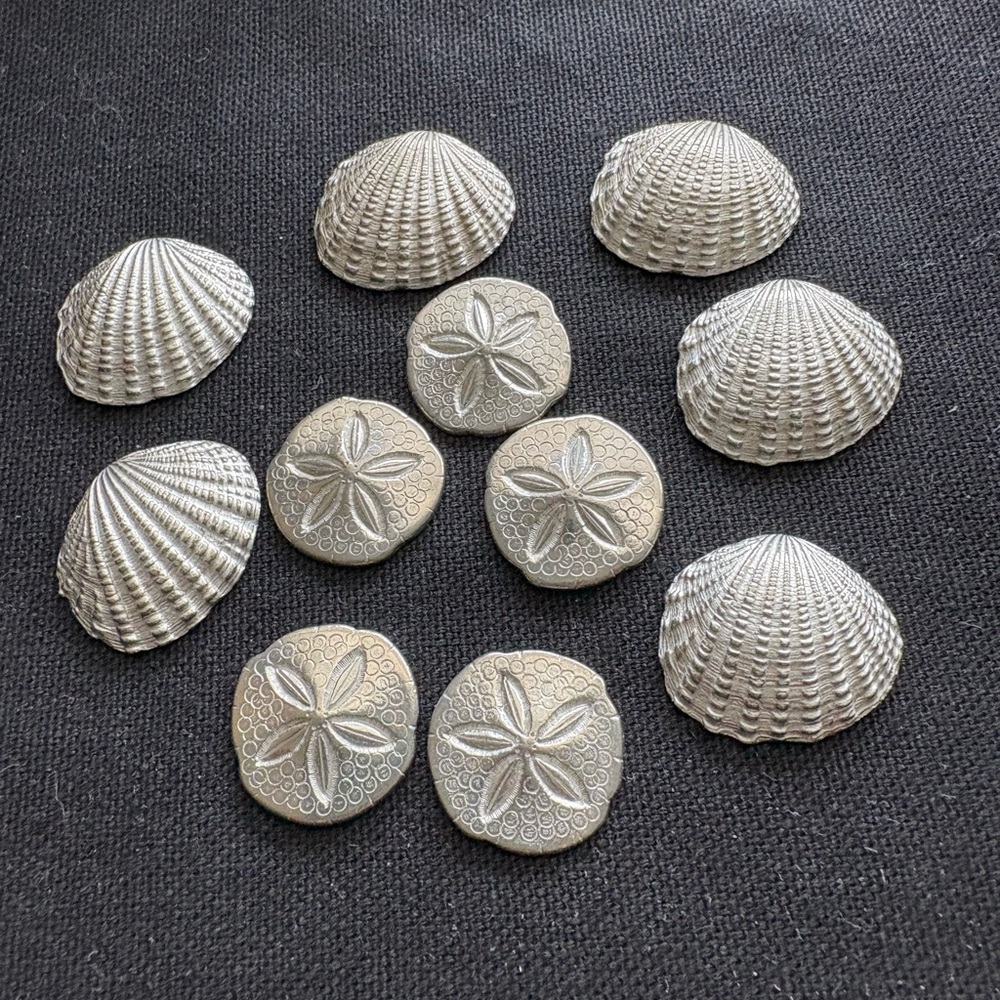 11 silver tone shell pocket tokens in bag.